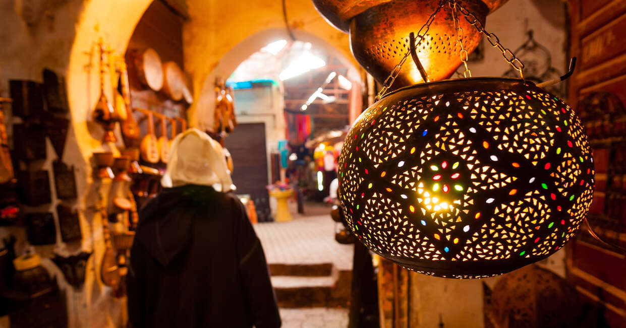 A woman walks past a lantern shop in a Marrakech souk